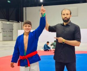 روحالله نظری، نامی که با اراده، تلاش و غیرت گره خورده است. او تنها یک ورزشکار نیست؛ نماد ایستادگی نسلی است که با وجود همهی سختیها، تسلیم نمیشود. در سرزمینی که راهها همیشه هموار نبودهاند، روحالله با باور به خود و عشق به ورزش، قدم برداشت و نشان داد که محدودیتها نمیتوانند رؤیاهای بزرگ را متوقف کنند.
او با هر تمرین، پیام امید را زنده نگه داشت و با هر قدم، ثابت کرد که ورزش میتواند زبان قدرت، صبر و هویت باشد. روحالله نظری نمایندهی شرافت ورزش افغانستان است؛ کسی که با تلاش خاموش اما مداوم، الهامبخش جوانانی شد که هنوز به فردای بهتر ایمان دارند.
نام او یادآور این حقیقت است که قهرمانی فقط روی سکو نیست؛ قهرمان واقعی کسی است که در سختترین شرایط، ایستادن را انتخاب میکند.